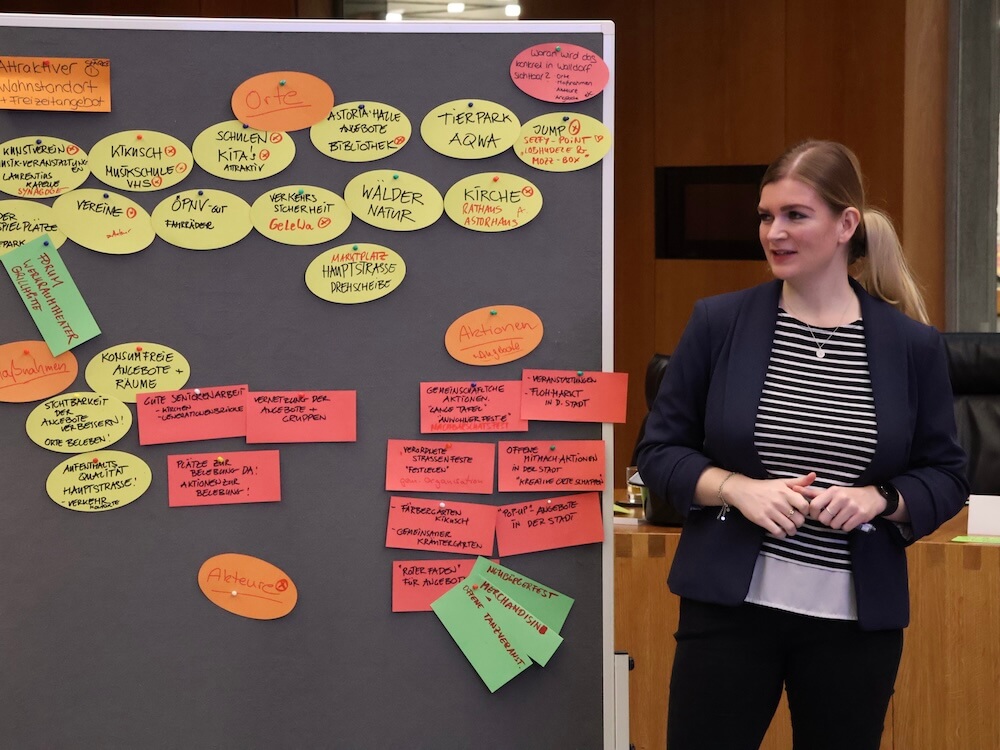 Sophie May steht nehmen einer Pinnwand und moderiert einen Workshop