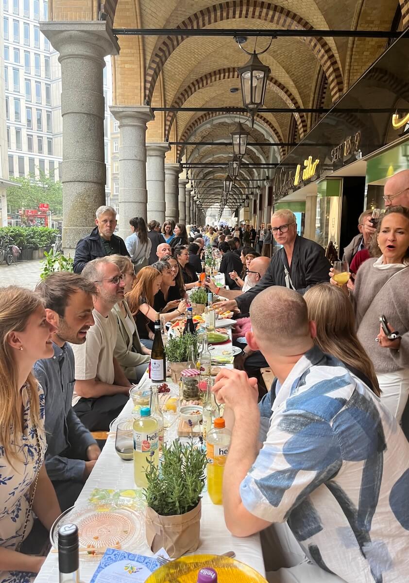 Menschen sitzen an einer langen Tafel in den Colonnaden Hamburg