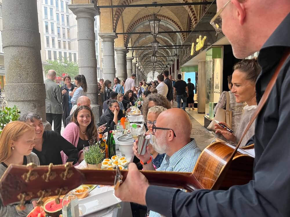 Menschen sitzen an einer langen Tafel in den Colonnaden Hamburg bei der Mediterranen Nacht