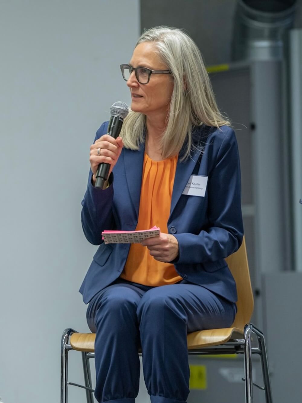 isabell-koester-close-up-credit-muhme-photography Isabell Köster sitzt auf der Bühne und spricht in ein Mikrofon