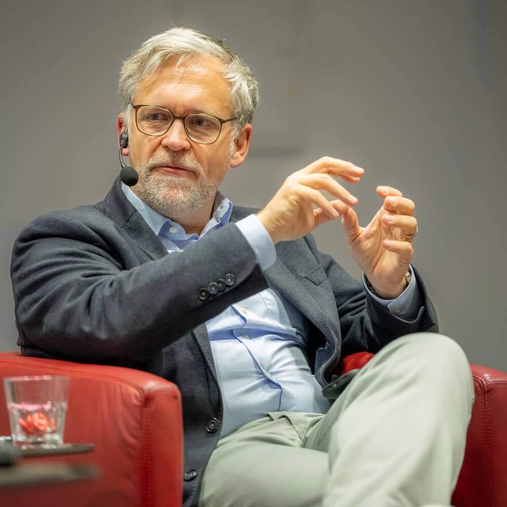 Thorsten Kausch sits with a microphone in a panel discussion on place branding and urban development