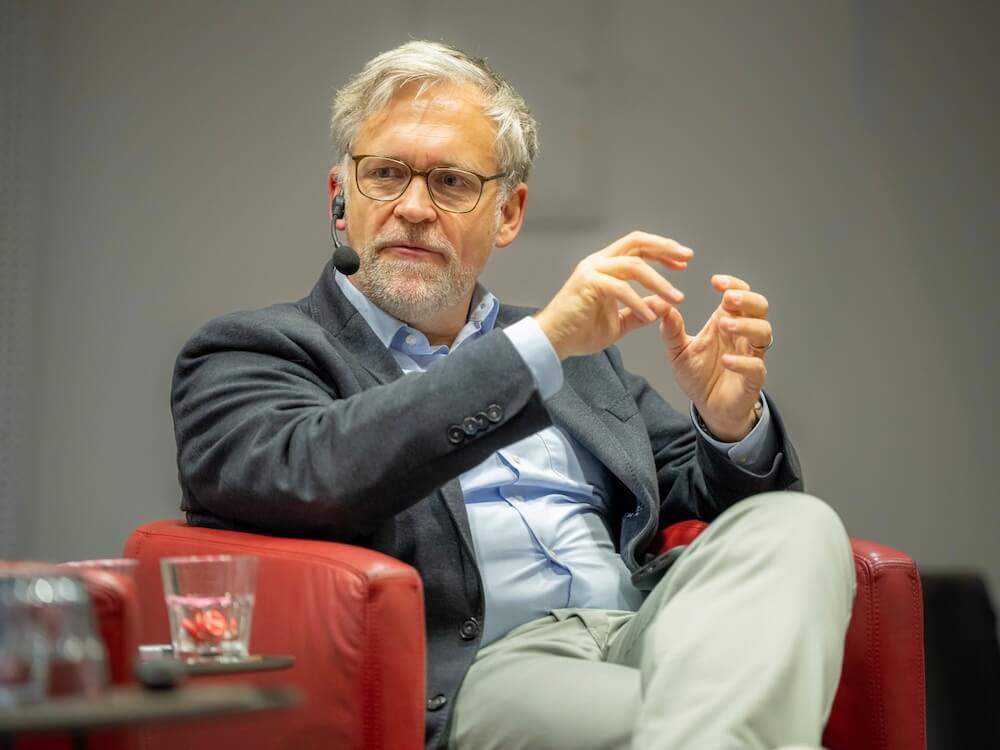 Thorsten Kausch sits with a microphone in a panel discussion on place branding and urban development