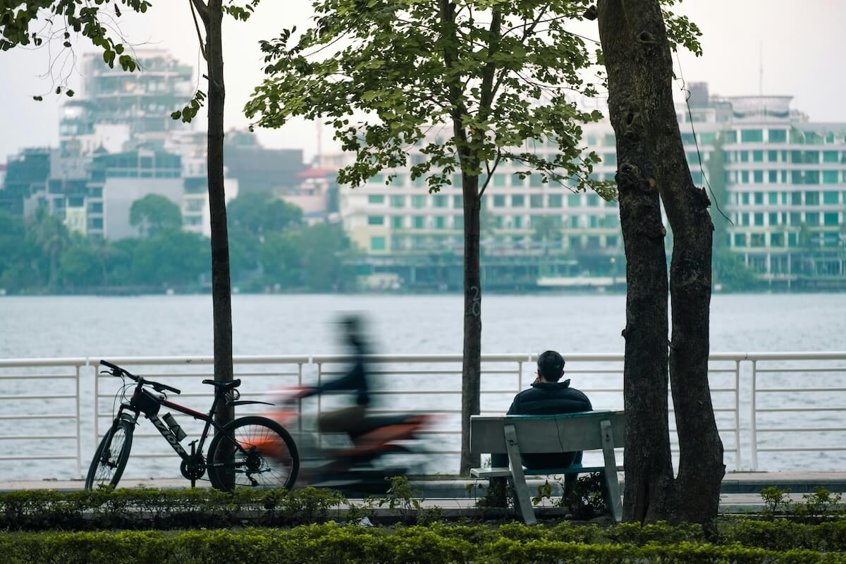 Mann sitzt am Ufer eines Flusses in einer Stadt