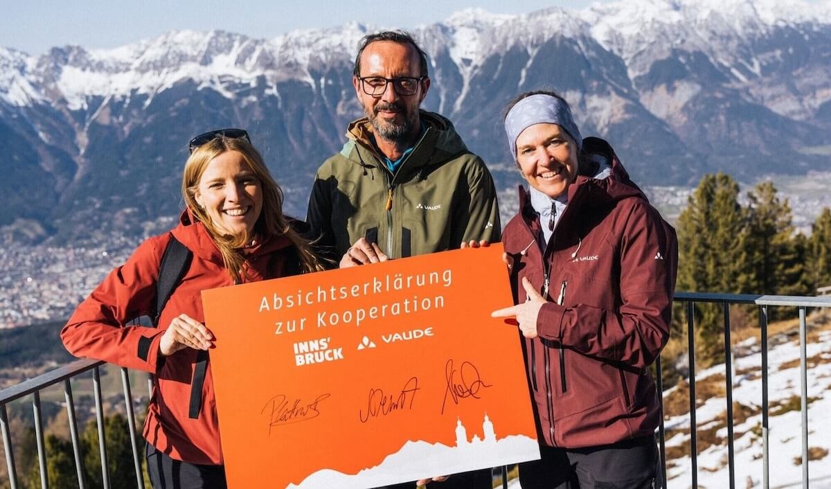 Representatives from Innsbruck Tourism and VAUDE pose for a photo against an Alpine backdrop