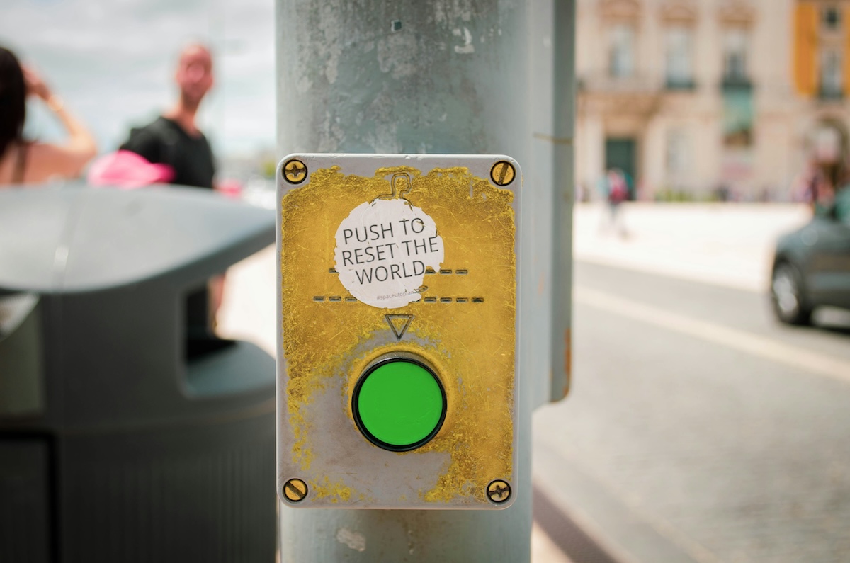 Ampelknopf mit einem Sticker mit der Aufschrift "Push to Reset the World"